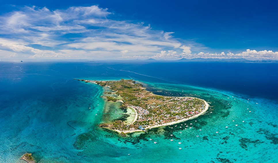 Aerial drone view of a small tropical island and surrounding coral reef (Malapascua)